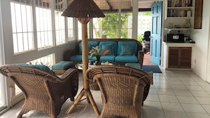 A room with wicker furniture, a ceiling fan, and a bookshelf. - Poinsettia Villa (Marigot Bay)