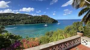 A coastal view with clear turquoise waters, a sailboat, and lush greenery. - Poinsettia Villa (Marigot Bay)