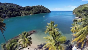 A coastal view with clear turquoise waters, palm trees, and a hilly landscape in the background. - Poinsettia Villa (Marigot Bay)