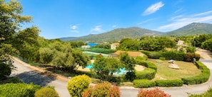 A residential area with a swimming pool, houses, and mountains in the background.