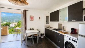 A modern kitchen with a dining area, a washing machine, and a view of the surrounding landscape. - T2 Dolce & Vita B4 sea and pool view (Propriano)