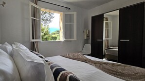 A bedroom with a bed, a window with curtains, a mirror, and a wardrobe. - T2 Dolce & Vita B4 sea and pool view (Propriano)