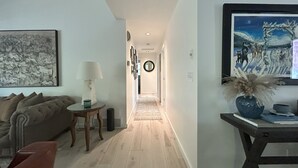 A hallway with a round mirror, a framed picture, and a vase with dried plants. - 4-bedroom house in highly desirable Southside Bozeman with AC and heated garage. (Bozeman)