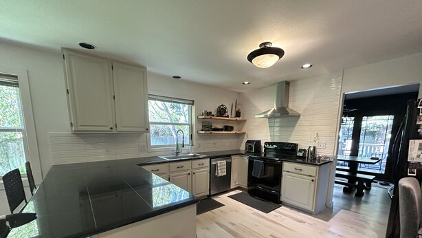 A modern kitchen with a large island, white cabinetry, and a view to the outside. - 4-bedroom house in highly desirable Southside Bozeman with AC and heated garage. (Bozeman)