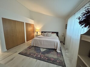 A bedroom with a bed, nightstand, lamp, and a large wardrobe.