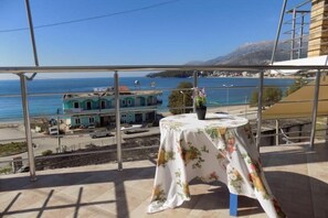 Un balcón con una mesa y una planta en maceta, con vistas a un pueblo costero y al mar.