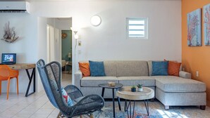 Un salon comprenant un canapé, une table basse ronde, un fauteuil en osier et une petite table sur laquelle se trouve un ordinateur portable.