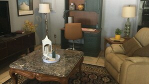 Un salon comprenant une table basse en marbre, un canapé, un meuble en bois et un téléviseur.
