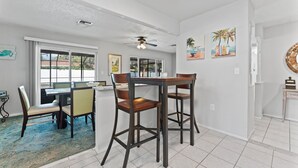 A dining area with a table and chairs, a ceiling fan, and artwork on the walls. - Charming 3-bedroom house with WiFi, AC in Palm Harbor (Palm Harbor)