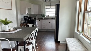 A modern kitchen with white cabinetry, a wooden ceiling, and a dining area with a bench and chairs. - Cottage in Sugarcreek with Hot Tub (Sugarcreek)