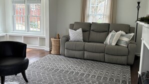 A living room with a grey sofa, a black armchair, and a patterned rug. - Cottage in Sugarcreek with Hot Tub (Sugarcreek)