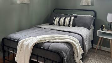 Ein Schlafzimmer mit einem Bett, einem Nachttisch, einer Lampe und einem gemusterten Teppich.