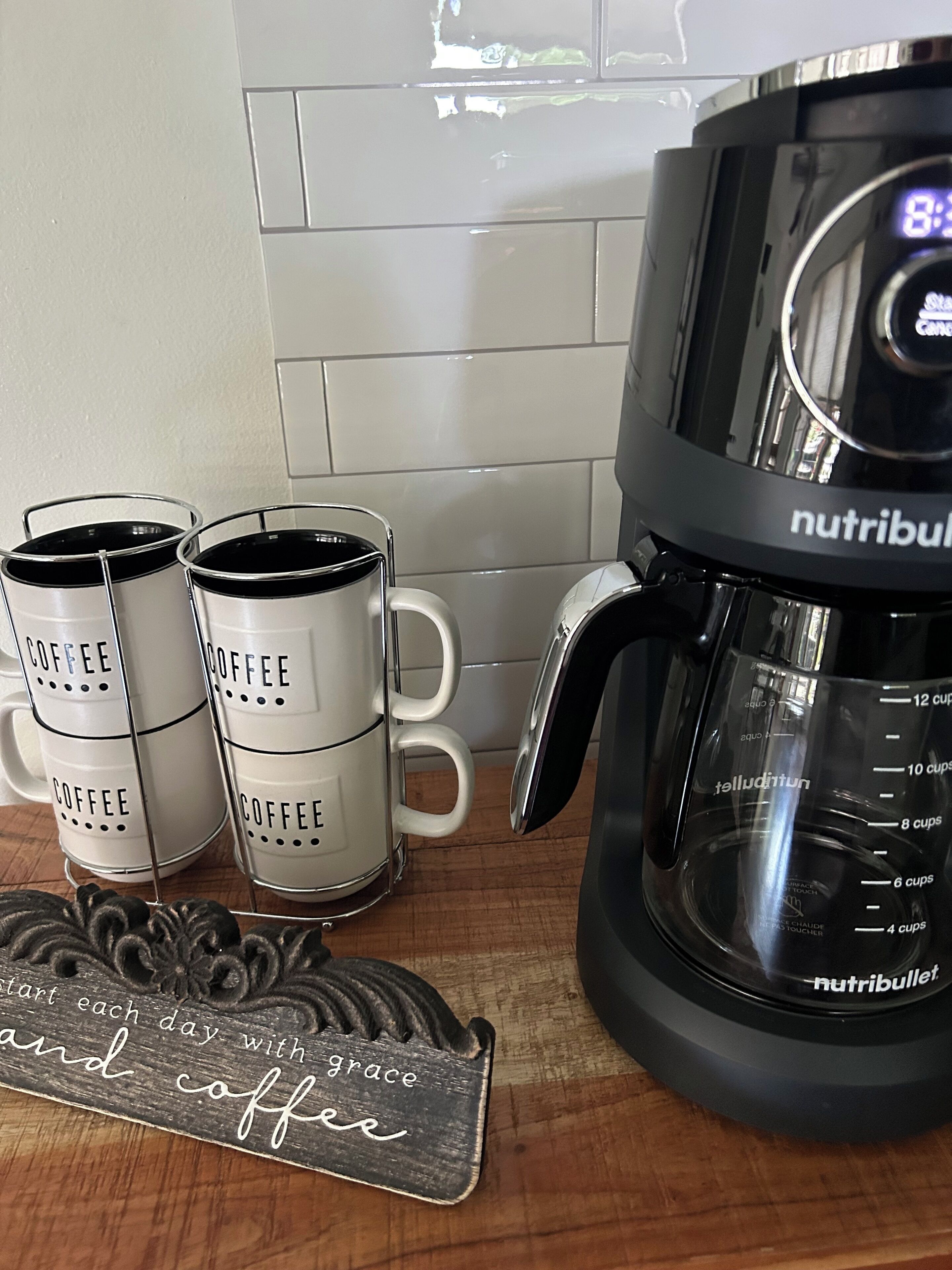 Una cafetera, dos tazas de café y un letrero de madera con texto.