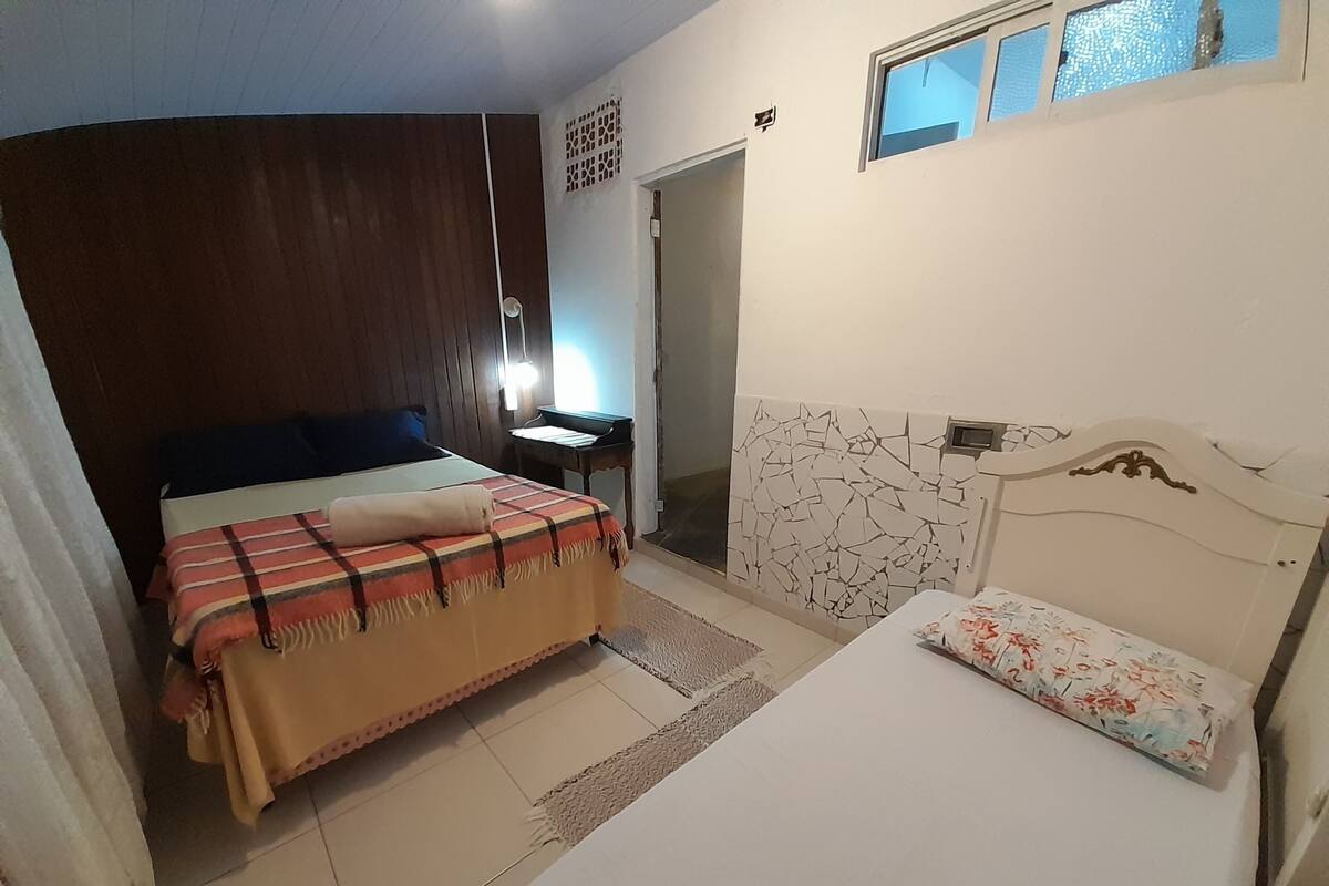 A bedroom with two beds, a desk, and a piano.