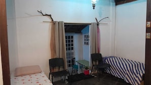 A small, compact room with a bed, two chairs, a table, and a window. - Casa Jardim Secreto II (Penha)