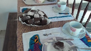 A table set with a teapot, cups, a plate with a cake, and a decorative mat. - Casa Jardim Secreto II (Penha)