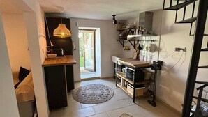 Eine kleine Küche mit Essbereich, einer Treppe und Blick ins Freie.