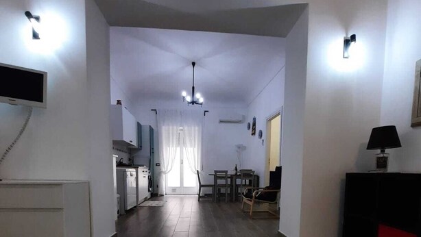 A spacious living area with a marble floor, a dining table, and a kitchen in the background. - Cozy apartment, ideal for families, in the heart of Ortigia (Siracusa)