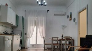A spacious living area with a kitchen, dining table, and a comfortable seating area. - Cozy apartment, ideal for families, in the heart of Ortigia (Siracusa)