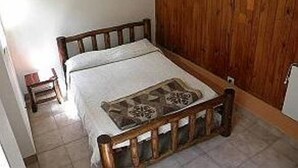 A small, single-bed room with a wooden headboard, a bedside table, and a hanging light fixture. - Club Hostel (San Salvador de Jujuy)