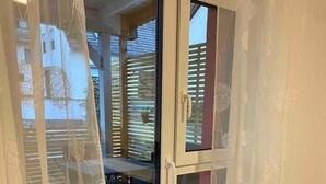 A room with a sliding glass door leading to an outdoor area, featuring a wooden deck and a table with chairs. - Sit back and relax with us between the Moselle and the vineyards. (Mehring)