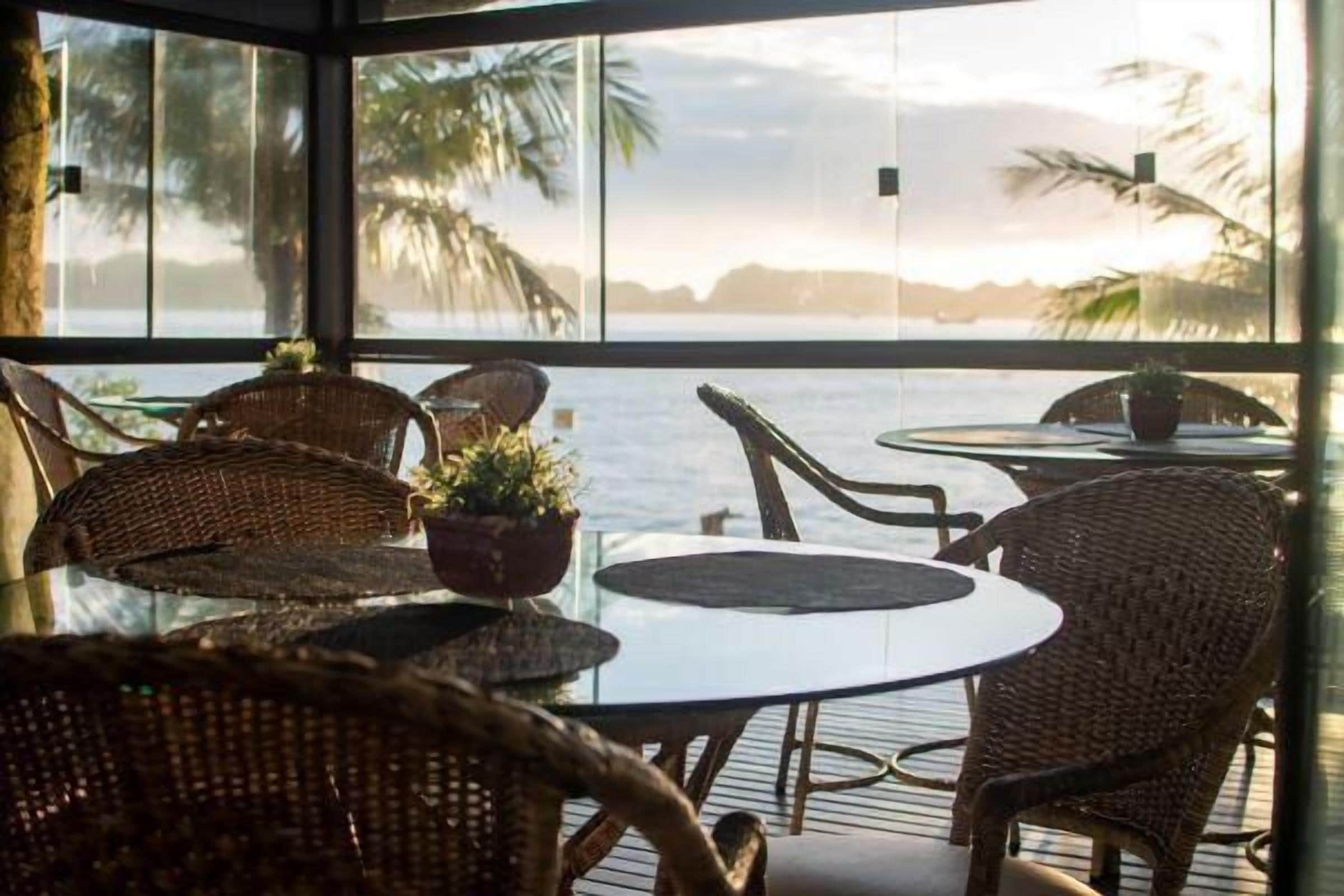 Un espacio de estar techado al aire libre con mobiliario de mimbre y vistas al mar.