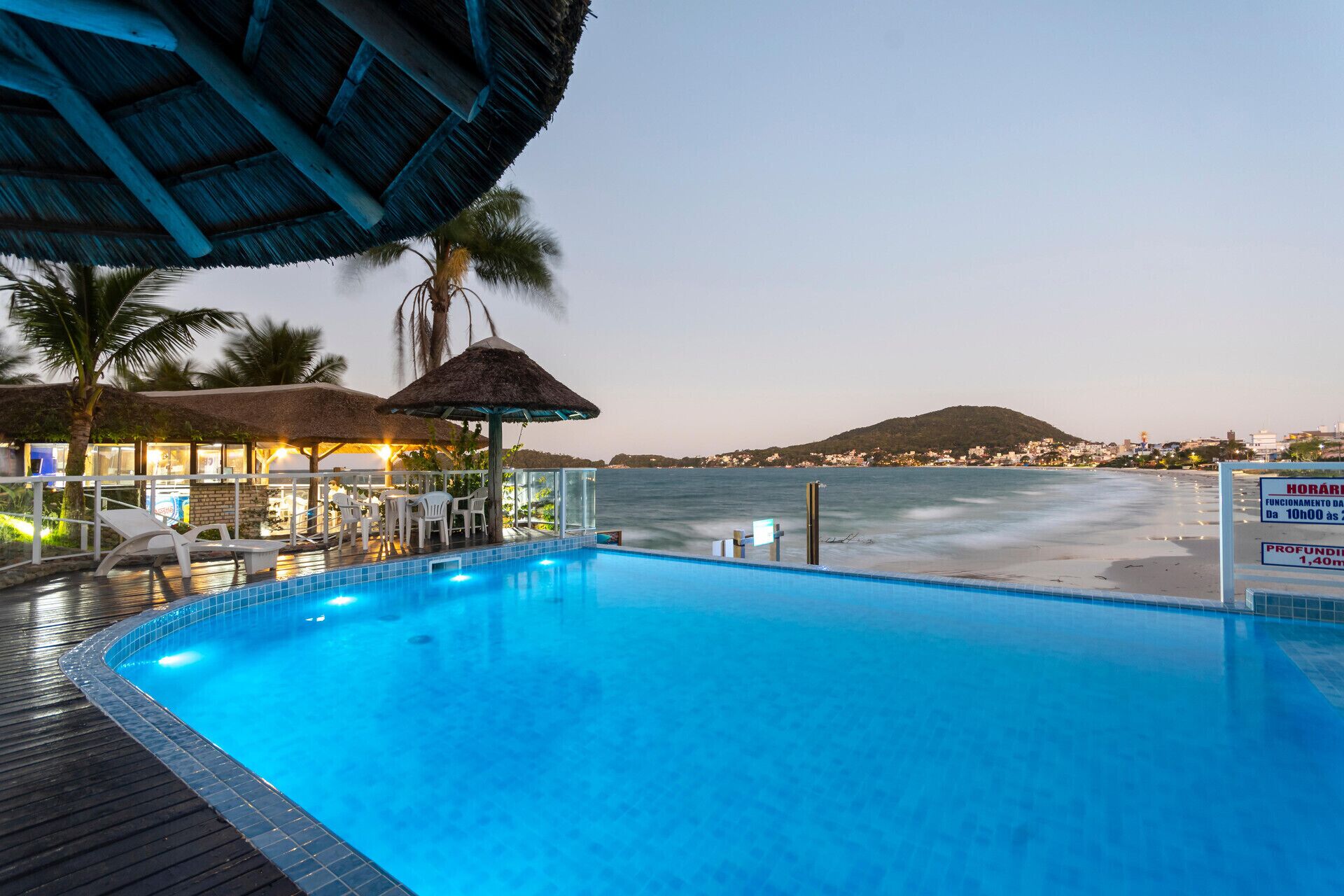 A swimming pool with a view of the beach and a mountain in the background.