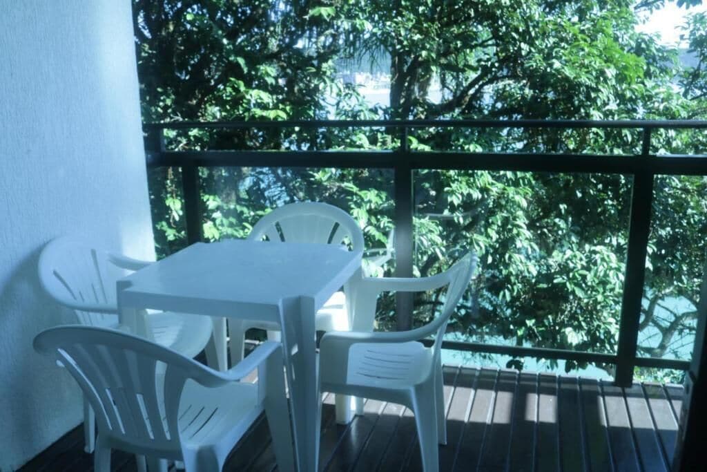 Un balcón con una mesa y sillas, con vistas a una zona verde exuberante.