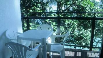 Un balcón con una mesa y sillas, con vistas a una zona verde exuberante.