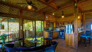 A wooden cabin with a kitchen, dining area, and large windows. - Ocean & Forest Views, Wildlife, Pool, Beach, Family & Friends, A/C....5 Star! (Uvita)