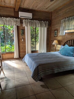 Una stanza in legno con un letto, tende e un condizionatore d'aria.