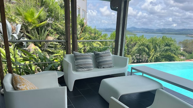 Un espacio al aire libre moderno con mobiliario blanco y una piscina.