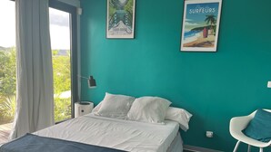 Un dormitorio con cama, una silla, una mesita de noche y dos cuadros en la pared.