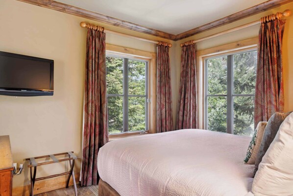 A bedroom with a large bed, a flat-screen TV mounted on the wall, and a window with curtains. - Villa Montane 226 - 4 Bedroom (Beaver Creek)