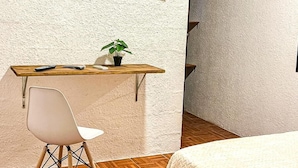 A room with a bed, a desk with a chair, a television mounted on the wall, and an air conditioning unit. - Eco Suite (Treinta y Tres)