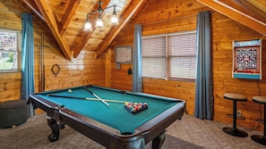 A pool table with balls, a clock, and a dartboard in a wooden room with a sloped ceiling. - Romantic Hideaway • Hot Tub, Scenic Views, Dogs OK (Pigeon Forge)