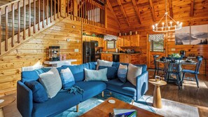 A wooden cabin interior with a living area, kitchen, and dining space.