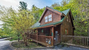 A log cabin with a porch, surrounded by trees. - Romantic Hideaway • Hot Tub, Scenic Views, Dogs OK (Pigeon Forge)