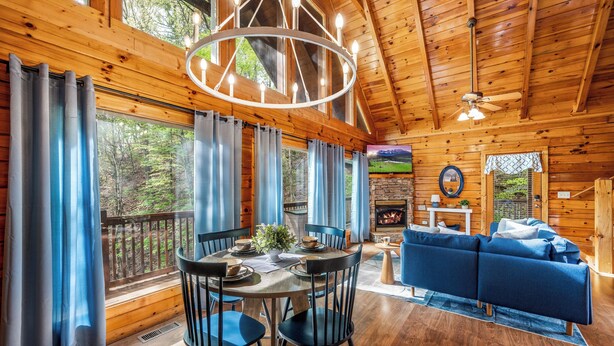 L’intérieur d’un chalet en bois comprend un coin repas, un canapé bleu et une cheminée.