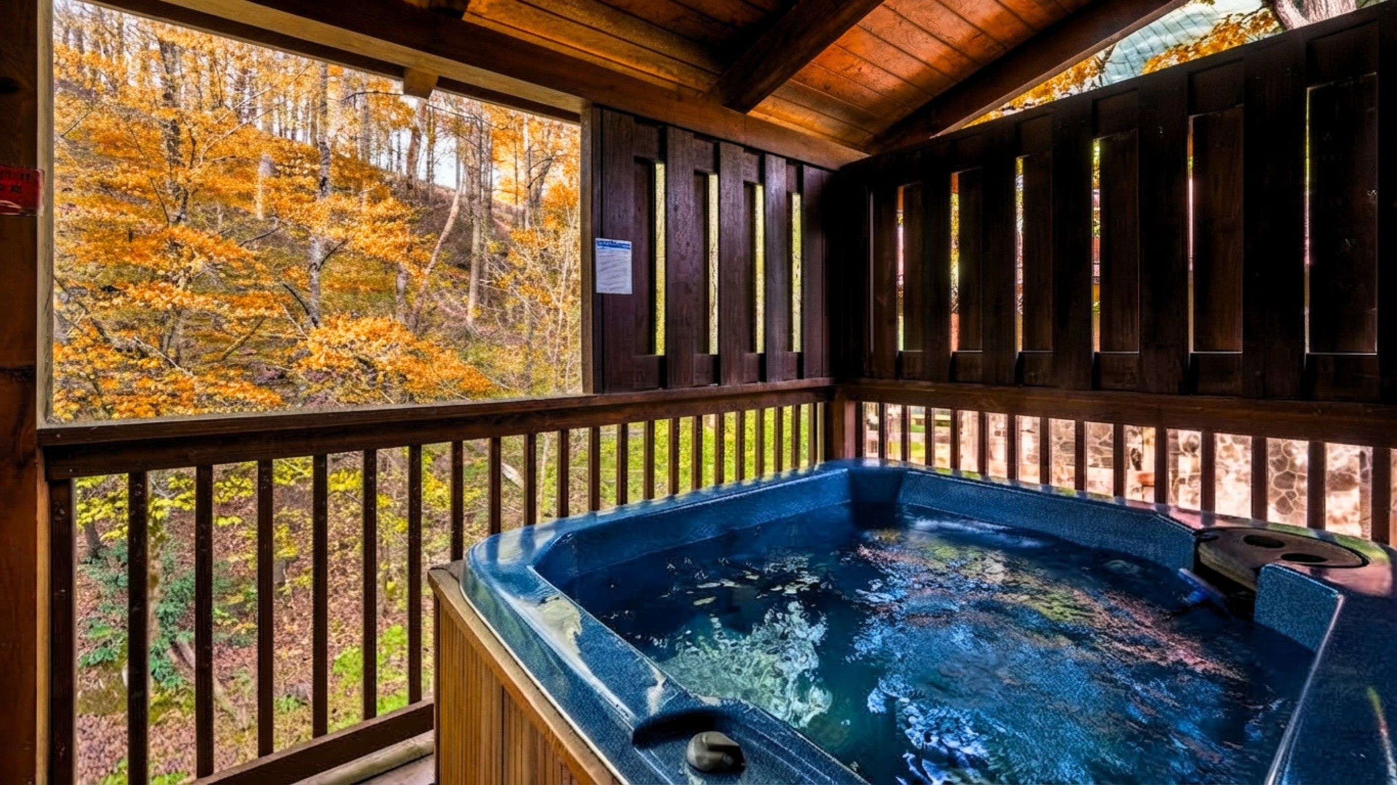 A hot tub with a wooden deck and a view of autumn foliage.
