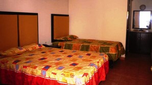 A room with two beds, each with a colorful quilt, a wooden headboard, and a small mirror above a dark wooden dresser. - Hotel Catedral (Torreón)