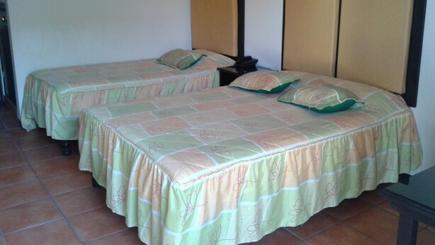 A room with two beds, each with a headboard, a nightstand, and a wall-mounted telephone. - Hotel Catedral (Torreón)