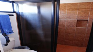 A compact bathroom with a toilet, a shower stall, and a towel rack. - Hotel Catedral (Torreón)