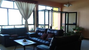 A living room with a leather sofa, a coffee table, and a potted plant. - Hotel Catedral (Torreón)