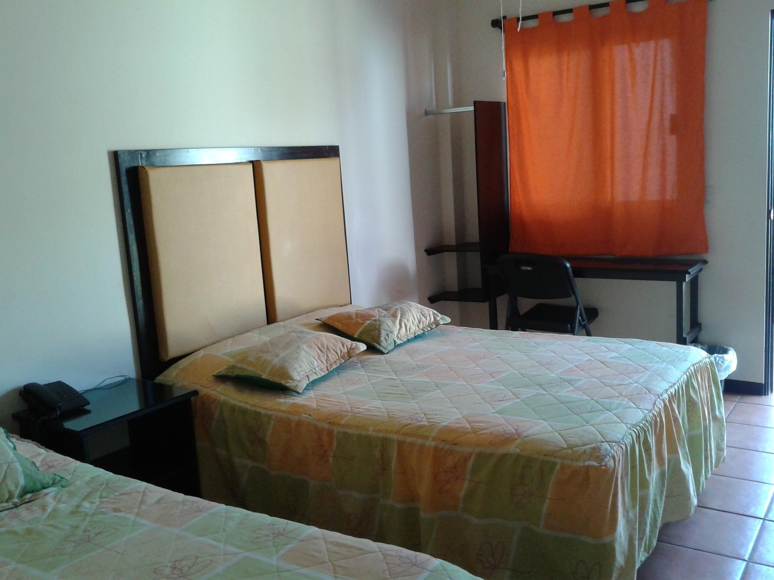 Habitación de hotel con dos camas, un escritorio y una silla.