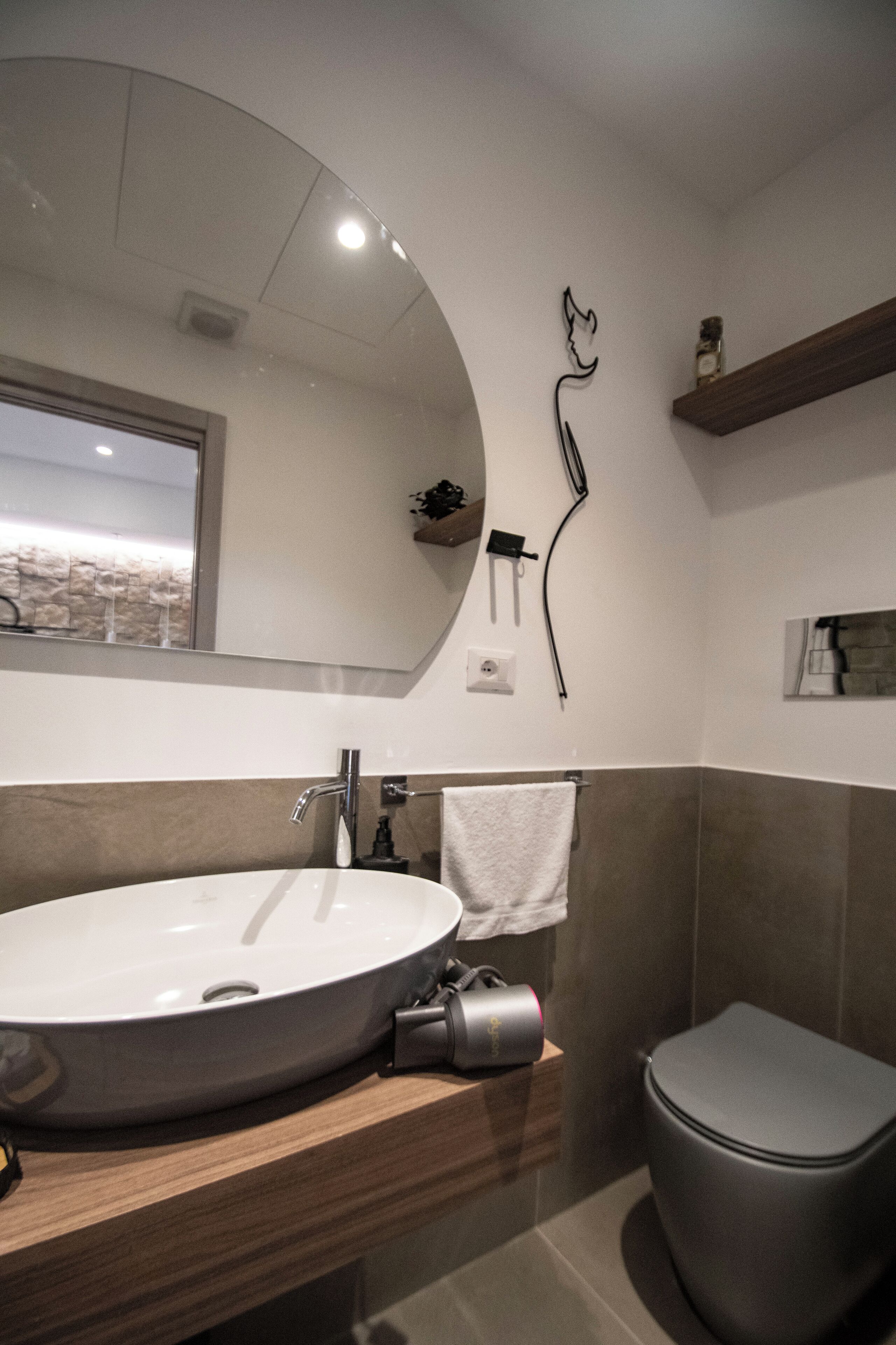A modern bathroom with a large round sink, a toilet, and a mirror above the sink.