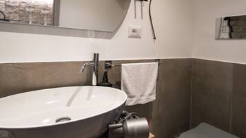 A modern bathroom with a large round sink, a toilet, and a mirror above the sink.