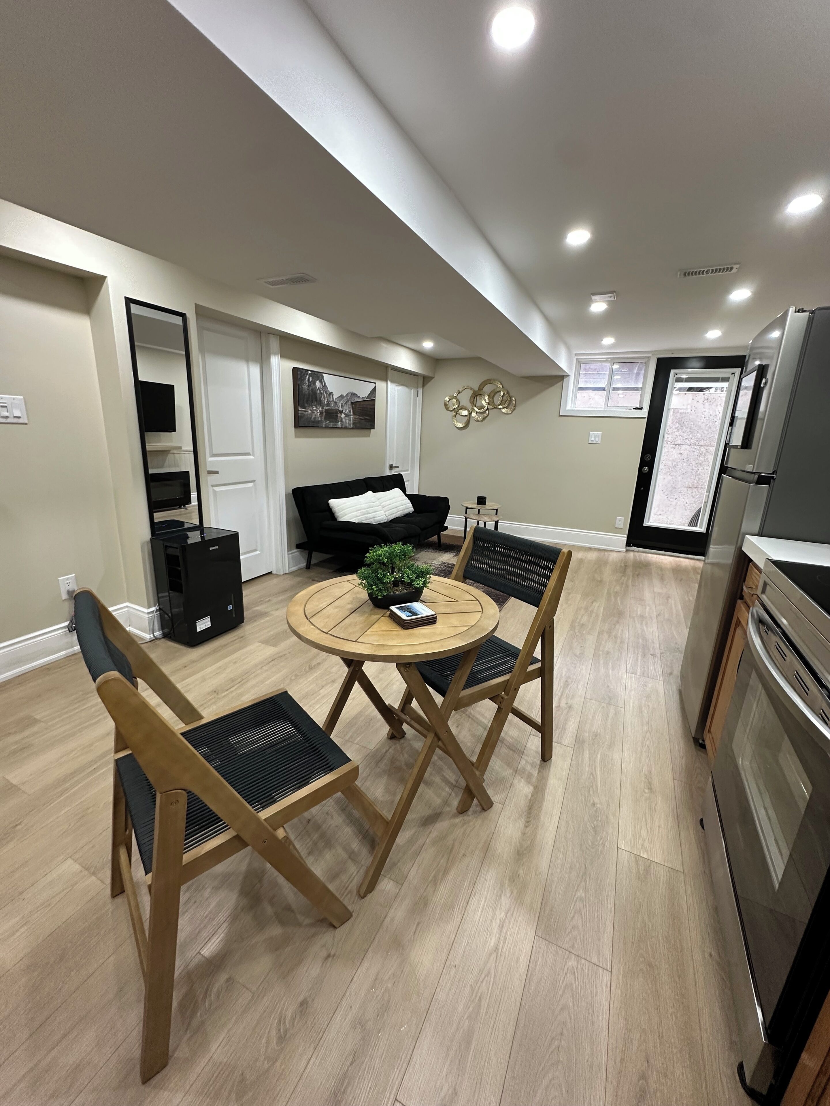 Una cucina moderna con zona pranzo, un divano nero e una televisione.