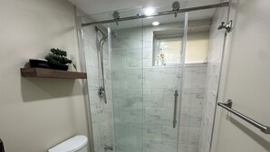 A modern bathroom with a glass-enclosed shower, a toilet, and a vanity with drawers. - The Perfect Getaway (Orangeville)
