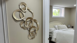A bedroom with a bed, a nightstand, and a wall-mounted decorative piece. - The Perfect Getaway (Orangeville)
